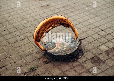 Old ground parking stopper with peeling paint and corrosion on paved pavement, top view highlighting weathered industrial surface. Selective focus. Stock Photo