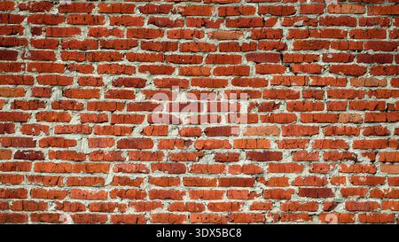 A weathered red brick wall with visible mortar and a rustic, aged texture. Close up. Stock Photo