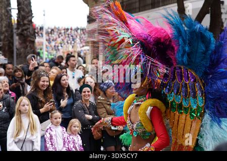 Vibrant performer in massive multicolored feather wings dances through the crowd in Menton's spectacular Fête du Citron parade.Menton,France Stock Photo