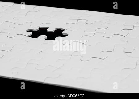 White Jigsaw Puzzle with One Missing Piece on Black Background Stock Photo
