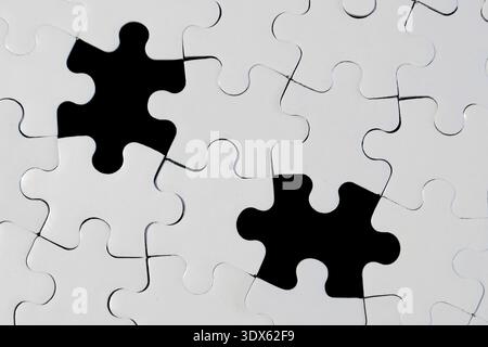 White Jigsaw Puzzle with Two Missing Pieces on Black Background Stock Photo