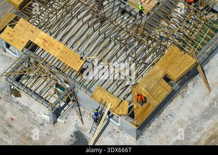 Builders working on roof construction of unfinished residential house with wooden frame structure in Florida suburban area. Housing development Stock Photo