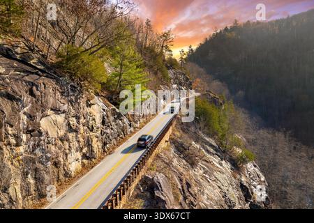 Highlands Road mountain highway in North Carolina during fall. Vehicle driving through forested hills and rocky ridgelines under colorful trees. Stock Photo