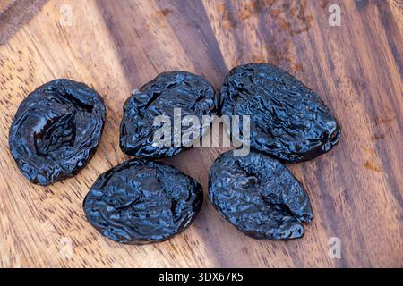 Dried Prunes on Wooden Surface - Natural Healthy Snack Close Up. Stock Photo