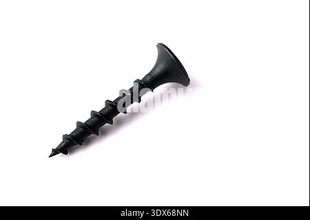 Black self tapping metal, screw white background.Black metal self-tapping screws on wood on a white table. Long black screws on drywall. Stock Photo