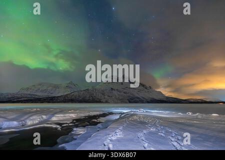 View of northern lights in the night sky on Skoddebergvatnet lake. Grovfjord, Troms county, Northern Norway, Norway. Stock Photo