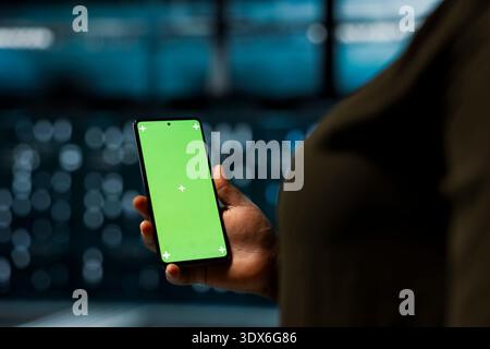 Close up of data center software developer using green screen smartphone to optimize network. Worker manages server hub equipment rigs resources with mockup phone for improved reliability Stock Photo