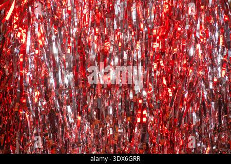 A mesmerizing display of red and silver glittering tinsel creates an abstract, glowing background. The bokeh effect adds depth and texture, evoking fe Stock Photo