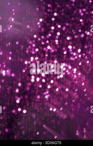 Abstract glowing background featuring shimmering purple bokeh and glitter elements. The soft focus and vibrant lighting create a dreamy and festive te Stock Photo