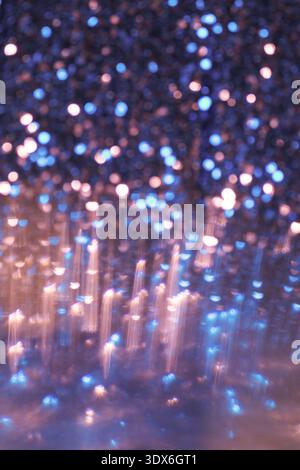 An abstract image featuring a glowing bokeh background in shades of blue and orange, creating a shimmering effect with glittery texture. Perfect for d Stock Photo