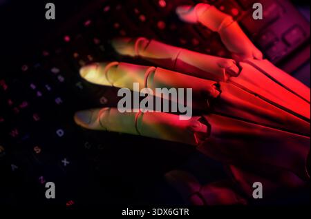 A cybernetic hand interacts with a keyboard, illuminated by dramatic red lighting, highlighting the fusion of technology and human interaction in mode Stock Photo