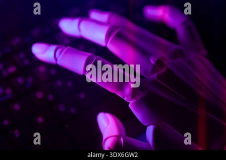 A robotic hand poised gracefully above a keyboard, aglow in purple light, illustrating the fusion of technology and artificial intelligence in modern Stock Photo