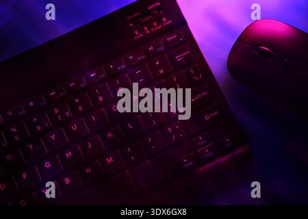Close-up of a keyboard and mouse, with vibrant purple light highlighting just part of the mouse, creating a modern, tech-savvy vibe perfect for AI and Stock Photo