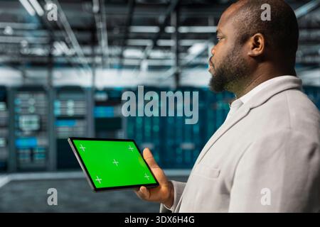 Close up of computer scientist in data center using green screen tablet to check for server performance issues. Server hub employee fixing bugs slowing down gear using mockup device Stock Photo
