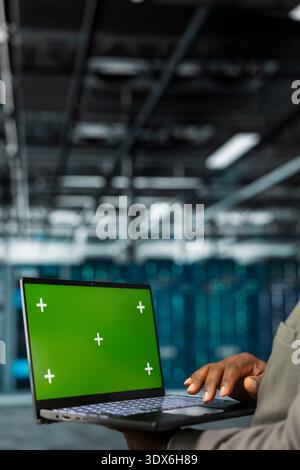 Close up of technician using green screen laptop in data center, managing rackmounts systems. Server hub employee using mockup notebook, installing upgraded infrastructure Stock Photo