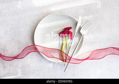 Elegant spring table setting featuring a simple white plate, silver cutlery, and vibrant pink flowers, adorned with a delicate pink ribbon on a textur Stock Photo