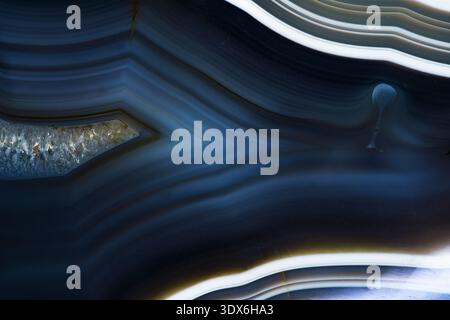 Close-up image of a natural blue agate stone, showcasing its intricate layered textures and subtle color variations. The fascinating patterns highligh Stock Photo