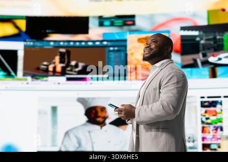 Cheerful man browsing curated video recommendations on smartphone streaming service. Happy man enjoying free time exploring favorite online entertainment clips on mobile phone Stock Photo