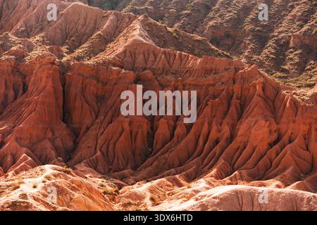 Detailed view of red sandstone formations in Fairy Tale canyon, Kyrgyzstan. Eroded ridge and layered texture shaped by wind and time in arid mountain Stock Photo
