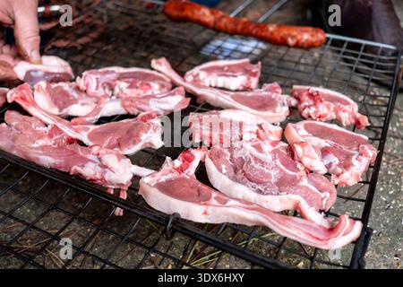 Raw lamb chops arranged on a grill, ready to be cooked over an open fire. A perfect scene for a barbecue, capturing the essence of outdoor cooking and Stock Photo