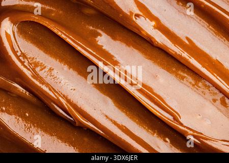 A close-up image of rich, smooth salted caramel showcases its glossy, creamy texture. The caramel's warm, inviting tones highlight its delicious appea Stock Photo