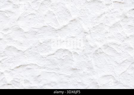 Close-up of a white wall featuring an uneven and textured surface. The rough patterns add depth and character, making it ideal for backgrounds or desi Stock Photo