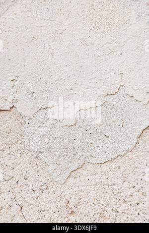 Detailed view of a weathered wall showing textured layers of paint and plaster. The surface has visible cracks and peeling areas, highlighting the eff Stock Photo