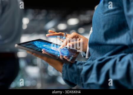 Close up of african american IT expert managing work on tablet, using neural network LLM visualization and artificial intelligence. Server farm supervisor overseeing deep learning process. Stock Photo
