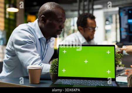 Green screen laptop used by programmers in Silicon Valley company office developing software apps. Mockup notebook used by IT professionals at work to code, debugging applications to resolve issues Stock Photo