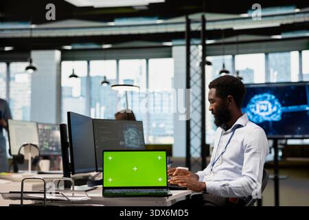 Tech startup office admin reviewing AI system metrics on isolated screen laptop, monitoring performance dashboards. African american man tuning neural networks using tools on mockup notebook Stock Photo