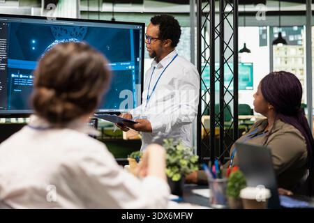 IT specialist in startup office doing presentation on machine learning to management. Computer scientist giving software development services pitch to CTO executives in AI tech agency Stock Photo