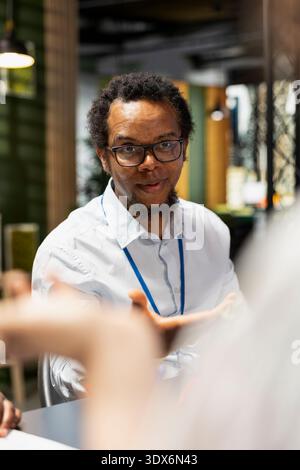 Team discussing during meeting in office, brainstorming software development issues. African american man talking with coworkers in startup company, doing code testing and quality assurance Stock Photo