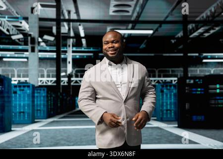 Smiling admin doing yearly checkup to prolong data center electronics life span and avoid downtime. Happy employee in server room monitoring server infrastructure components Stock Photo