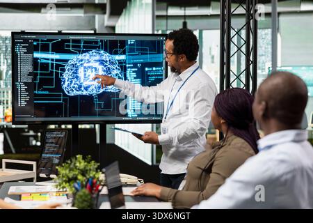 Startup coworkers discussing artificial intelligence tech roadmap during briefing session. Programmers developing AI applications in office, analyzing system performance metrics after QA testing Stock Photo