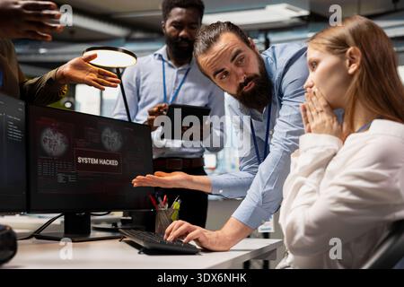 Worried team of programmers responding to hacking alert warning on screen, brainstorming solutions to fix security breach. Cybersecurity employees analyzing warning alert, working on countermeasures Stock Photo