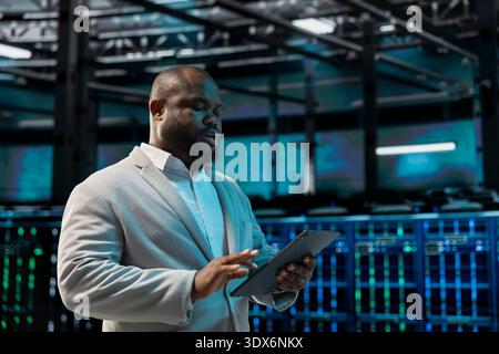 Computer scientist in data center runs system diagnostic tests on device, tracking resource utilization. Man in server hub scanning equipment, fixing network issues affecting rigs performance Stock Photo