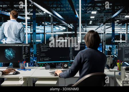 System administrator in server room using devices to review infrastructure diagnostics. IT expert in data center office analyzing performance data to maintain system uptime Stock Photo