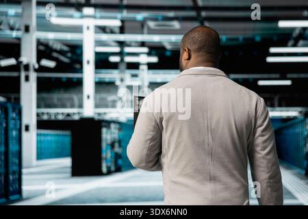 Technician working in data center overseeing international user traffic. IT professional walking in server room facility hosting websites and delivering web content to online customers Stock Photo