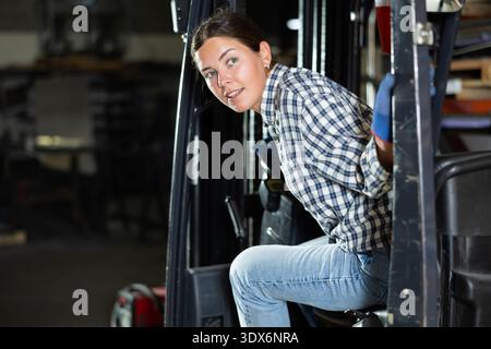 Young female worker operating forklift in industrial warehouse Stock Photo