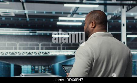 Technician walking in data center workplace with multiple rows of fully operational mainframes. Worker overseeing server farm built for storage enterprise solutions systems, camera B Stock Photo