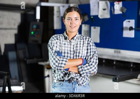 Smiling young female worker posing in metalworking workshop Stock Photo