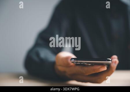 Close-up of a hand holding a smartphone with a blurred background. Stock Photo