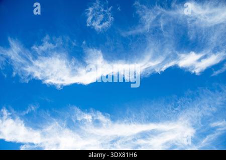 Delicate white clouds form ethereal patterns against a deep azure sky, suggesting a serene atmosphere and fair weather conditions Stock Photo
