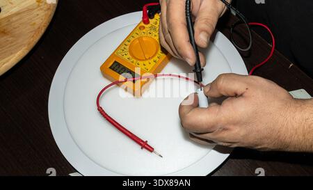 testing electrical connector with digital multimeter on led panel Stock Photo