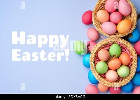 Colorful eggs in baskets with happy easter greeting on a blue background Stock Photo