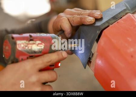 Close up focused hands of worker performing repair and maintenance. man using cordless drill power tool for construction assembly with screw in worksh Stock Photo