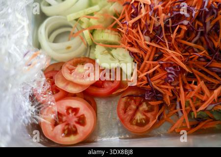 Vibrant mix of fresh cut vegetables for healthy salad. Sliced tomato, shredded carrot, onion, and red cabbage ingredients ready for delicious meal pre Stock Photo
