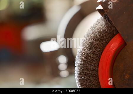 Close up wire brush wheel on an industrial grinder. rusty metal tool sits in workshop, conveying gritty, hardworking atmosphere and focus on industria Stock Photo