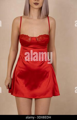 Woman in red satin nightgown posing while looking at the camera Stock Photo