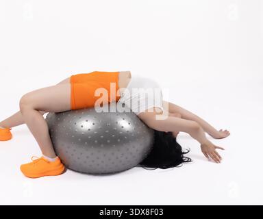Young lady lying on a fitness ball and stretching her back Stock Photo